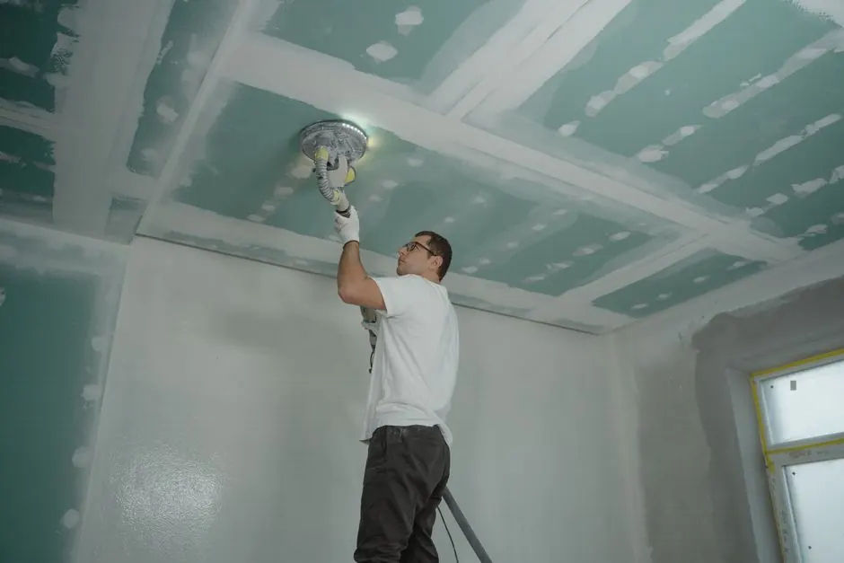 A worker expertly polishes a ceiling indoors, demonstrating home renovation skills.